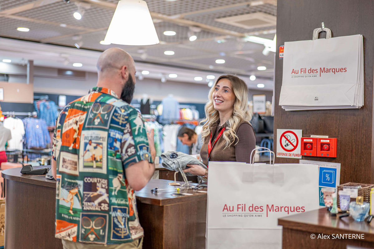 Conseillère Au Fil des Marques remettant ses achats à un client en caisse